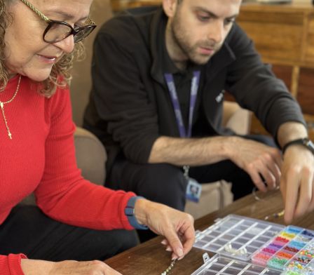 Female carer creating a necklace during a creative session
